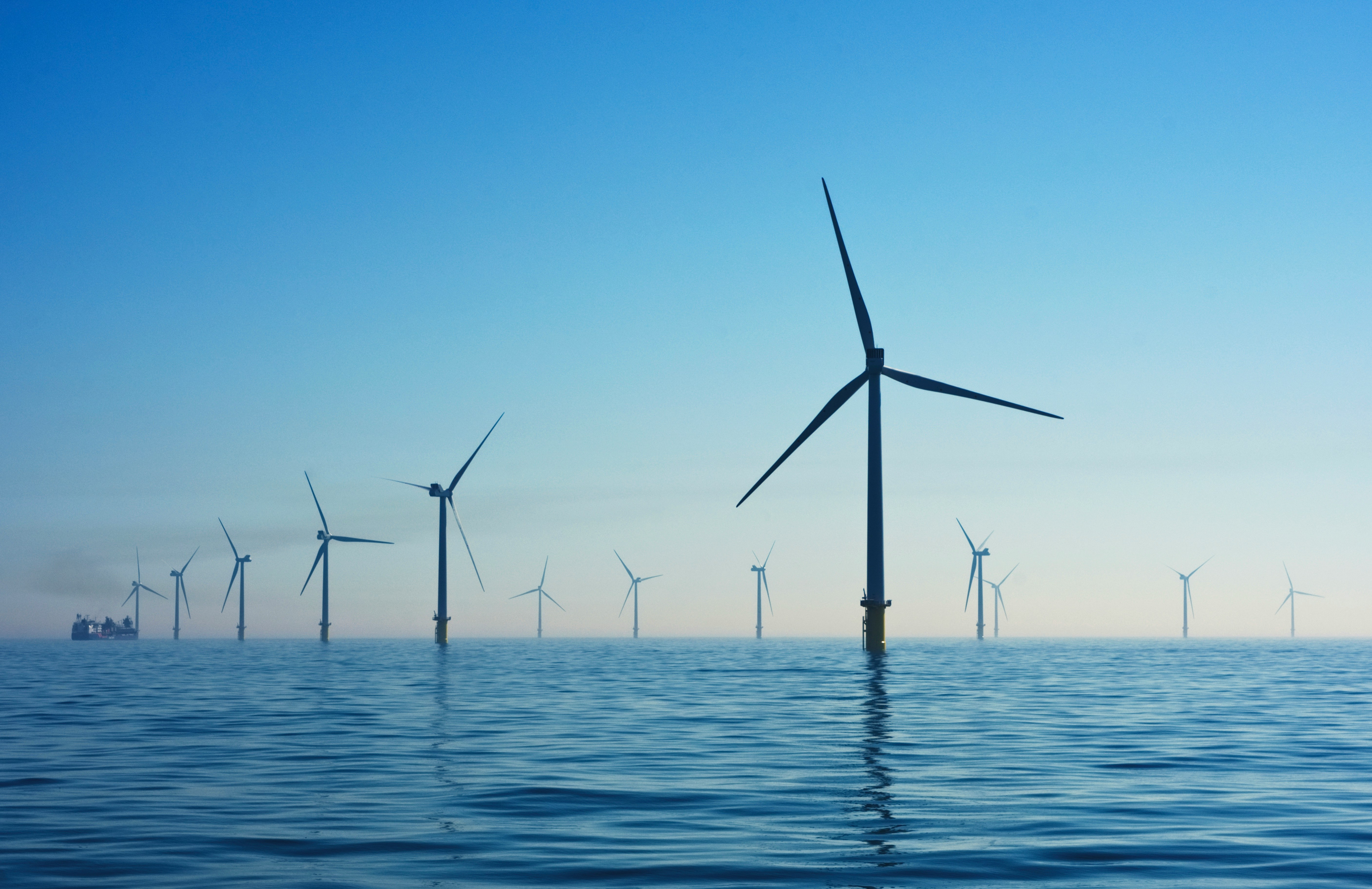 Windmills in the foreground and in the distance are part of an offshore windfarm.